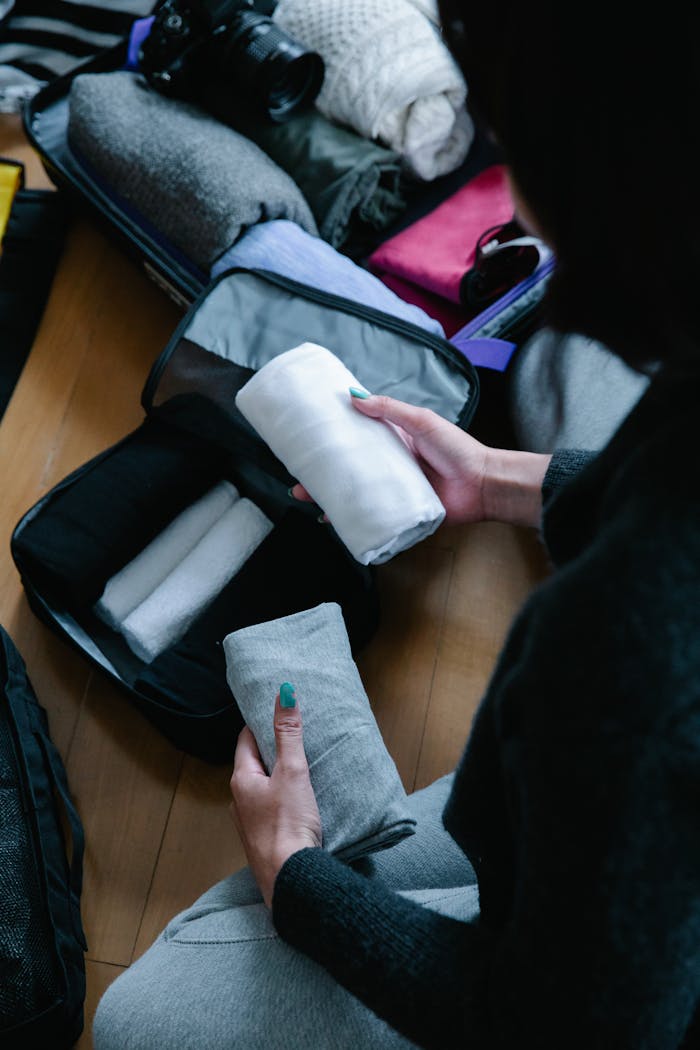 services-03 Person packing and organizing clothes in a suitcase for travel.