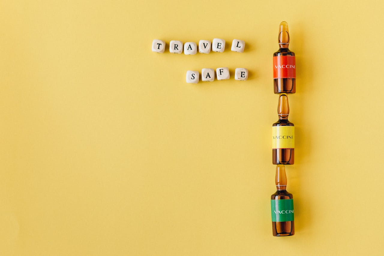 services-01 Three vaccine vials with a Travel Safe message arranged on a yellow background, conveying safety and health themes.