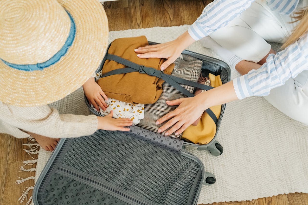 services-02 A woman and child pack clothes in a suitcase, preparing for a vacation.